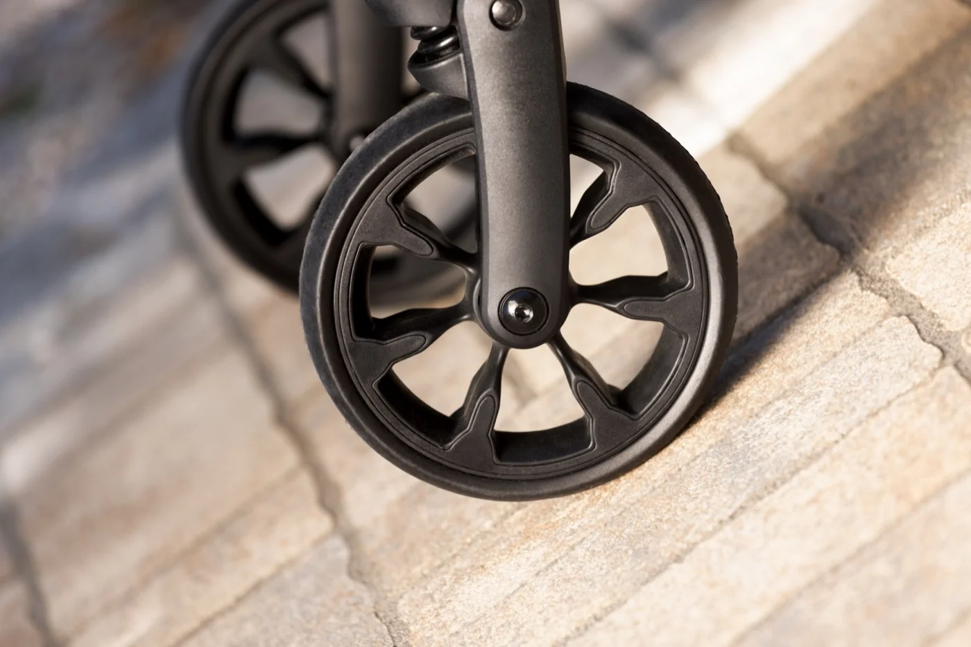 Front wheels of the MOON Dog dog buggy at the edge of a paving stone